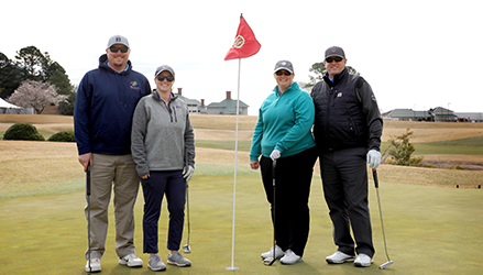 four golfers around pin