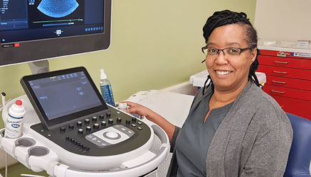 african american woman sitting at computer with sonogram image on the screen