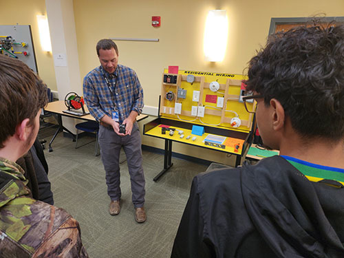 man showing electrical circuits to students
