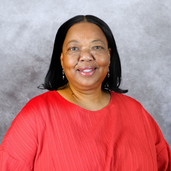A smiling woman in a red blouse with long black hair against a gray background.